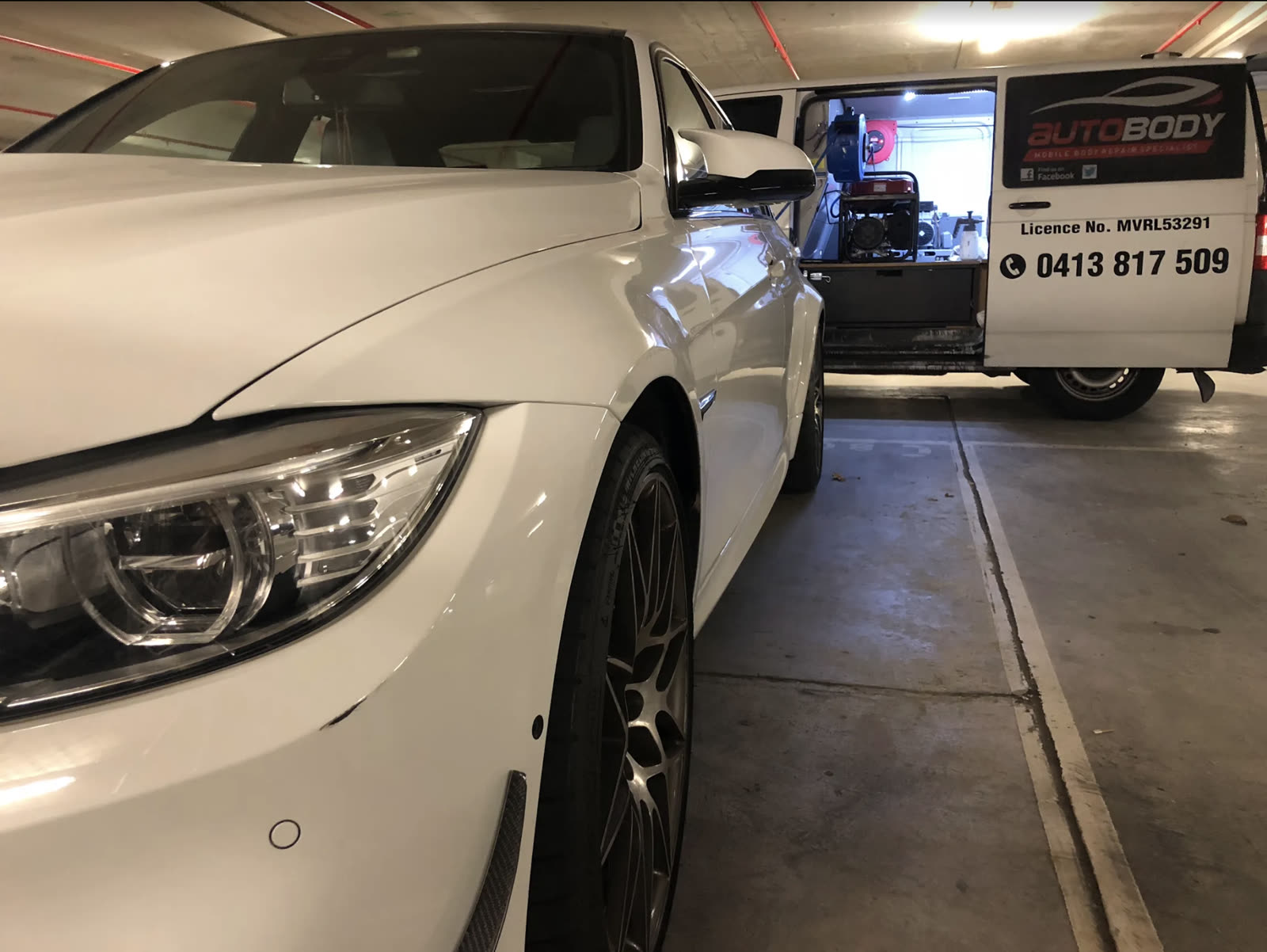 AB Autobody service van parked next to a white BMW being repaired on-site — licence MVRL53291, phone 0413 817 509 visible on the van
