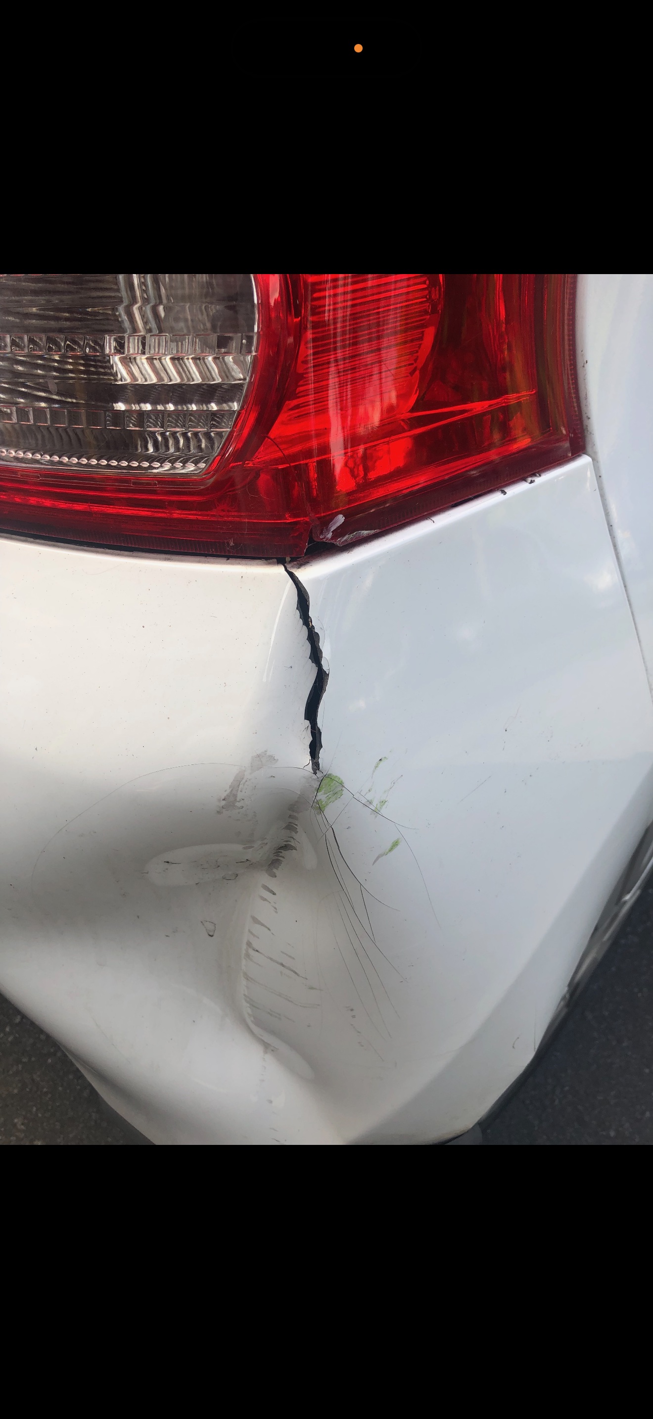 Cracked and split white rear bumper next to the tail light — the kind of plastic damage we rebuild by welding